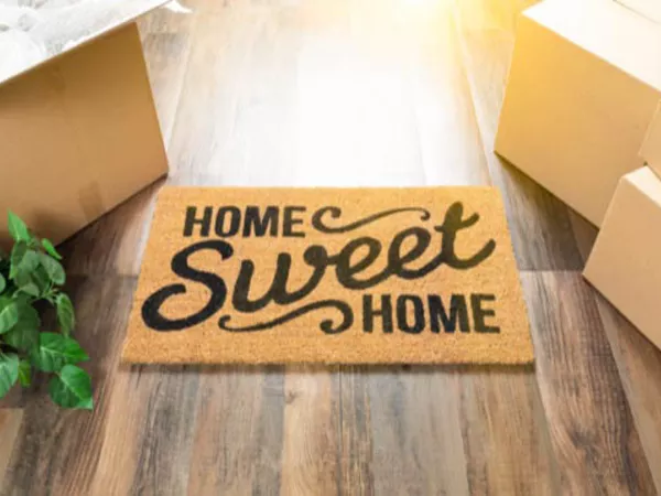 Welcome mat and moving boxes at the door of a housewarming party.