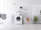 Washer and drying rack in a clean white laundry room.