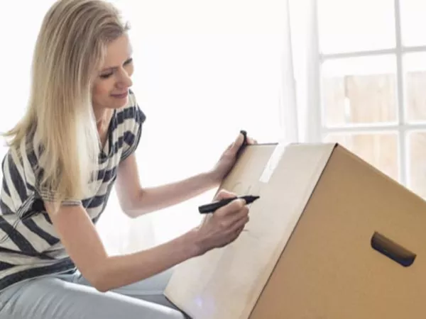 Woman writing on moving box.