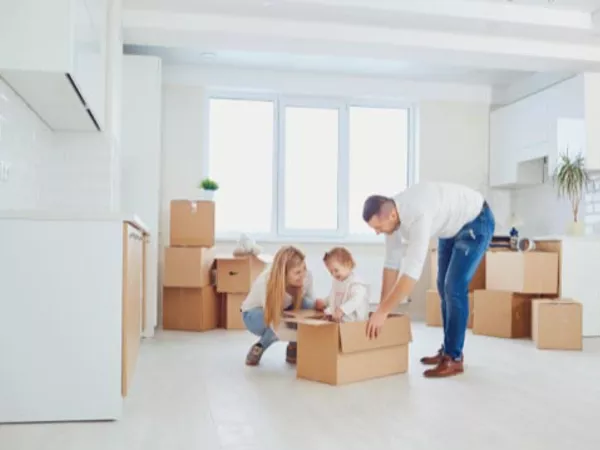 Mother, father and young daughter play in a moving box in their new kitchen.