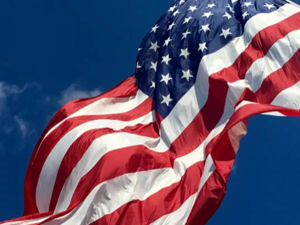 United States flag flying over a blue sky.