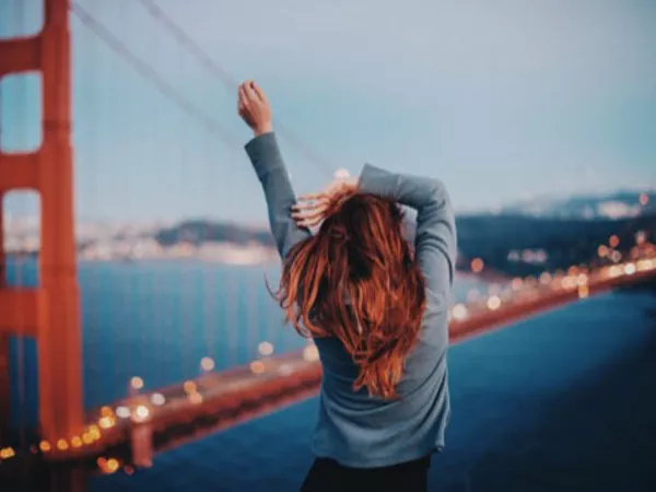 Woman looks excitedly over the Golden Gate Bridge as San Francisco is one of the best places to live in California.