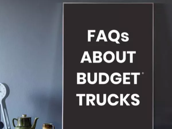 Sign on dark blue wall reading &quot;FAQs about Budget Trucks&quot;