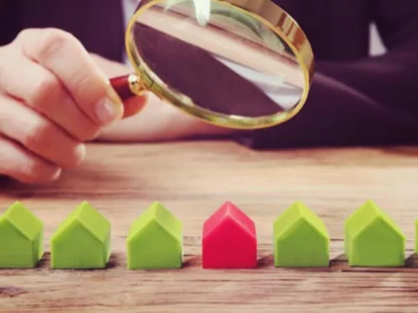 Person looking at miniature houses with a magnifying glass to find the differences between PODS and their competitors.