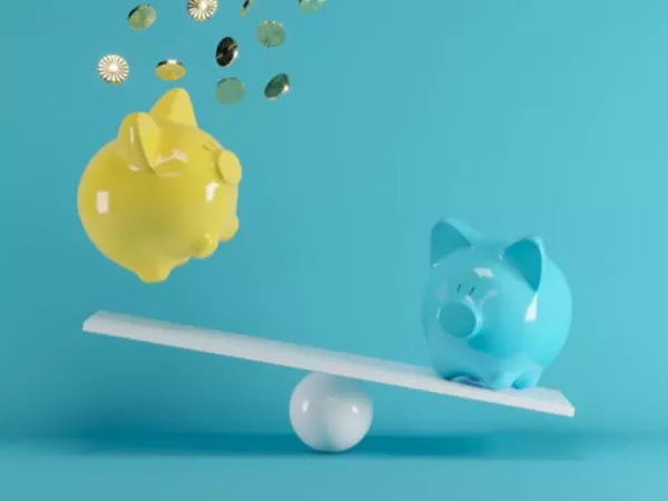 Two piggy banks on a balance scale with one surrounded by falling money, showing the savings from Penske moving truck coupons.