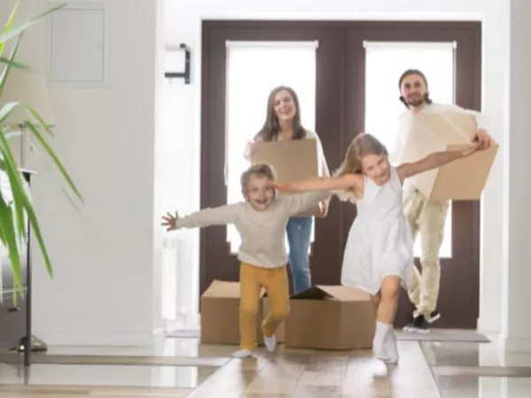 Family running into their new home carrying boxes after completing a long distance move.