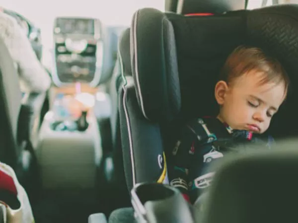 Sleeping baby riding in a car seat while the family is moving.