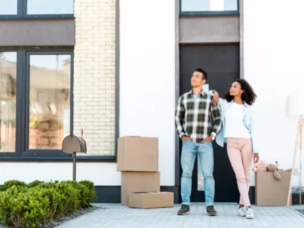 Couple standing outside their home before moving from Canada to the U.S.