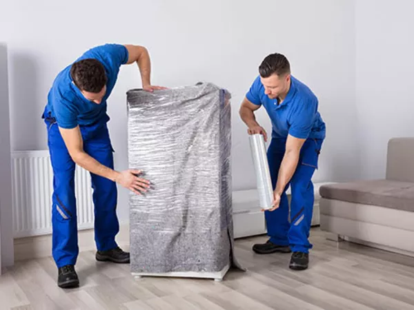 A person using plastic stretch wrap to protect furniture for moving.
