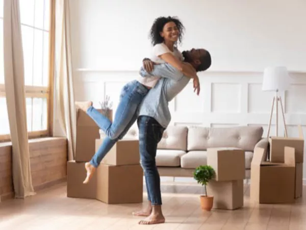Man and woman hugging among moving boxes, happy to be moving out of state.