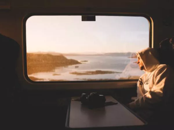 Man looking longingly out of the window of a train on the California coast.