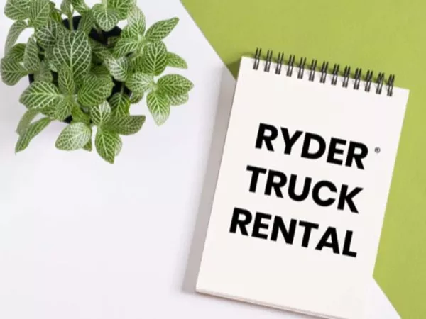 Notepad reading &quot;Ryder Truck Rental&quot; sitting on a table next to a plant.