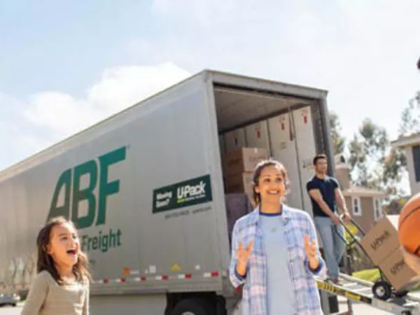 Family smiling as dad unloads the moving trailer after a state to state move.