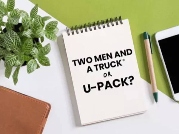 Notepad reading "Two Men and a Truck or U-Pack?" next to a pen and smartphone.