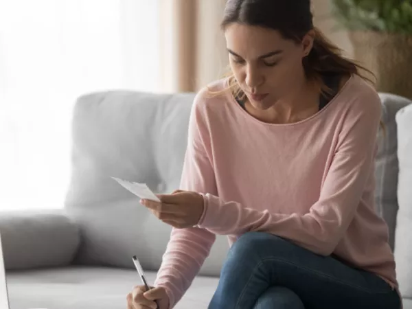 Woman using a pen, paper, calculator and online DITY calculator to estimate military moving costs.