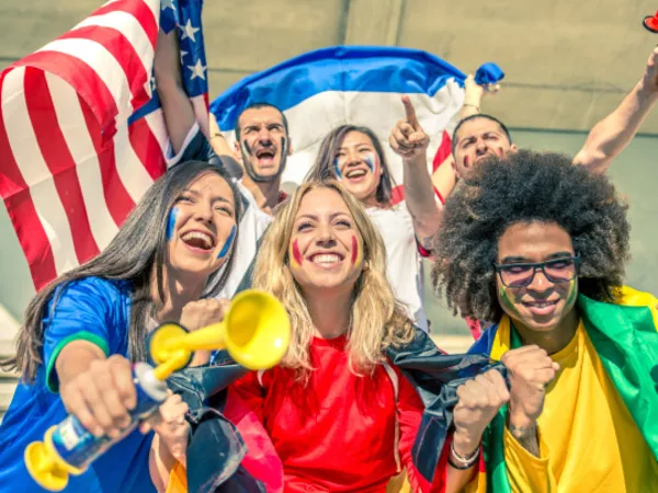 A crowd waves flags and air horns cheering on athletes at an Olympic venue.