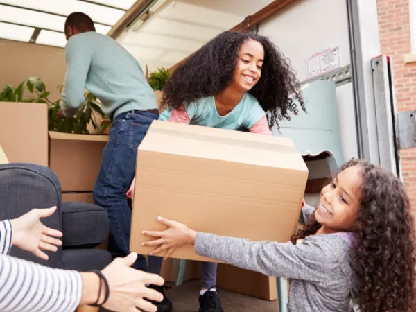 Two children help their parents unload a large U-Haul truck.