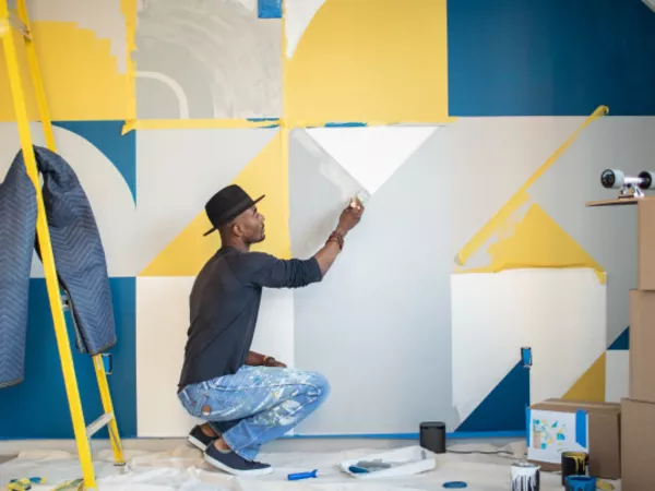 Man painting an accent wall with a geometric pattern.