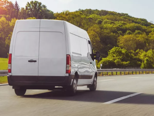 Small moving van driving on the road.