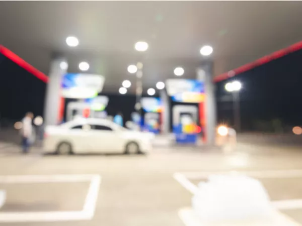 Car at a gas station with driver checking fuel prices before a long-distance move.