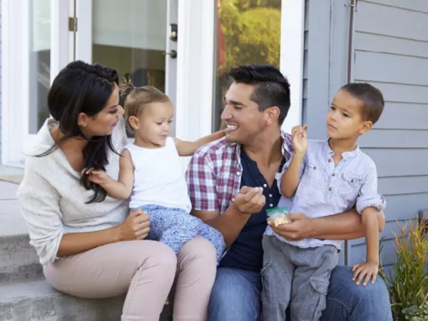 A family sitting outside their new home after moving to a new city.