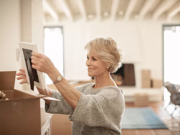 Senior woman unpacking a picture frame after moving.