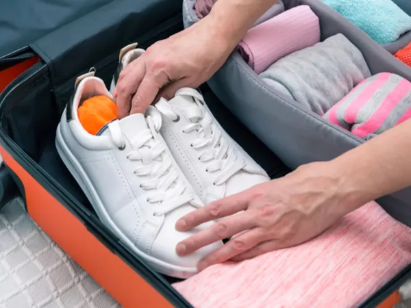 Placing shoes and other clothes in a suitcase.