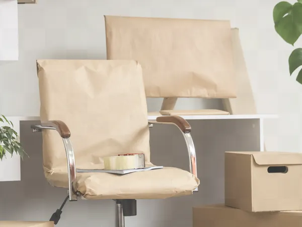 An office chair and computer monitor wrapped in paper padding for a move.