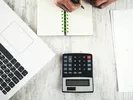 Person compares PODS cost to U-Pack with a laptop, calculator and pen and paper.