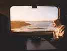 Man looking longingly out of the window of a train on the California coast.