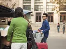Male student and parent unloading the car at a dorm after moving to college across the country.