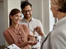 Man and woman accept keys on their short-term rental from a landlord.