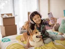 Girl sits on her bed with her dog before moving with her pet across country.