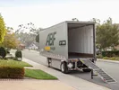 An empty U-Pack moving trailer sits on a residential street with ramp fully extended.